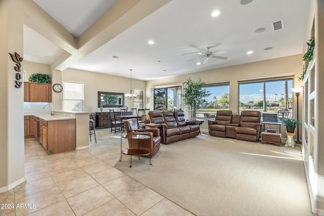 carpeted living room featuring ceiling fan with notable chandelier, plenty of natural light, and sink