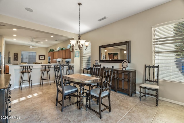 tiled dining space featuring ceiling fan with notable chandelier