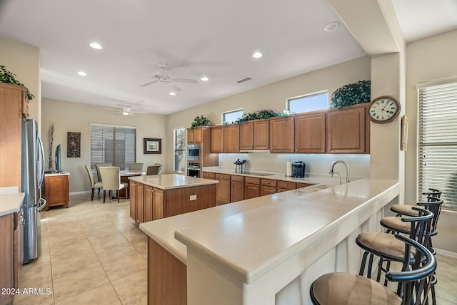 kitchen with a center island, sink, ceiling fan, light tile patterned floors, and stainless steel appliances