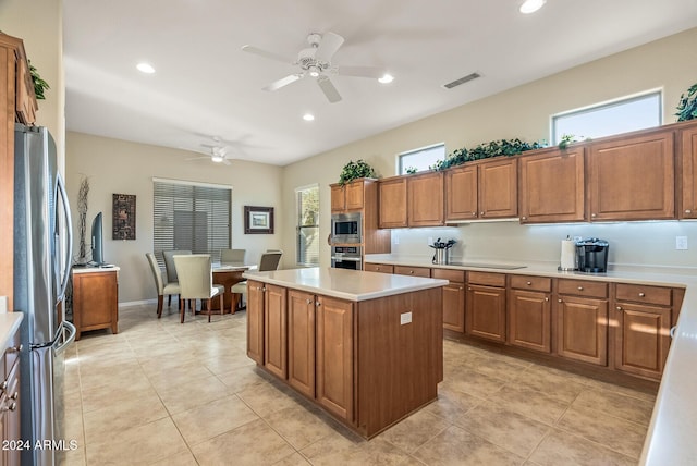 kitchen featuring light tile patterned floors, stainless steel appliances, a kitchen island, and ceiling fan