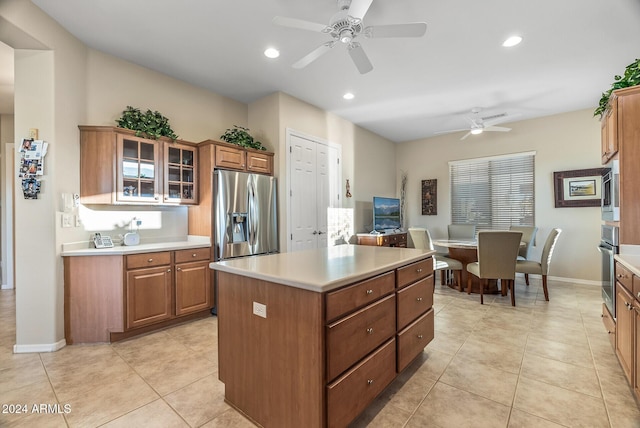 kitchen featuring ceiling fan, a center island, light tile patterned flooring, and appliances with stainless steel finishes