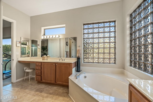 bathroom with tile patterned flooring, a bath, vanity, and a wealth of natural light