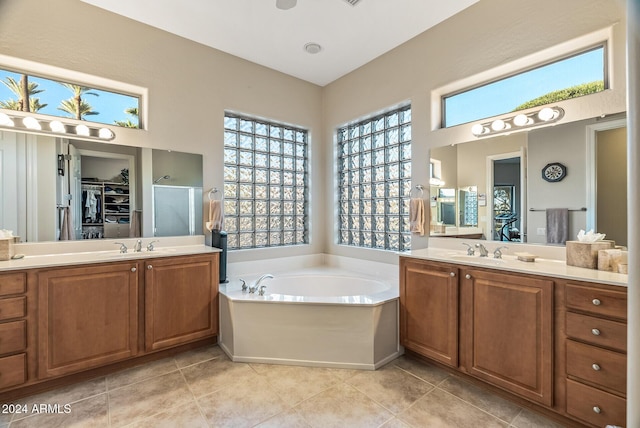 bathroom with tile patterned floors, vanity, plus walk in shower, and a wealth of natural light