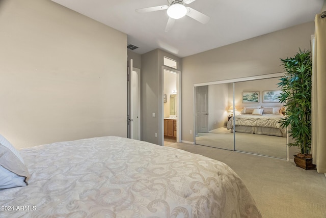 bedroom with connected bathroom, ceiling fan, a closet, and light carpet