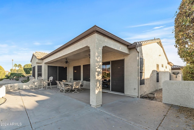 back of property featuring ceiling fan and a patio