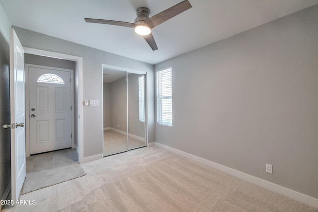 unfurnished bedroom with a closet, light colored carpet, and ceiling fan