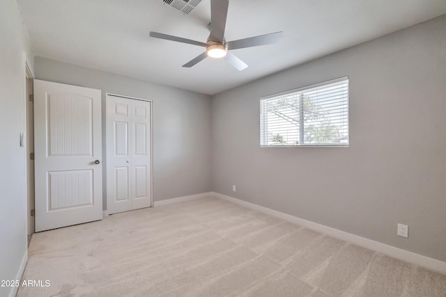 unfurnished bedroom with ceiling fan, a closet, and light colored carpet