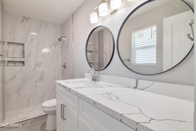 bathroom with toilet, tiled shower, and vanity