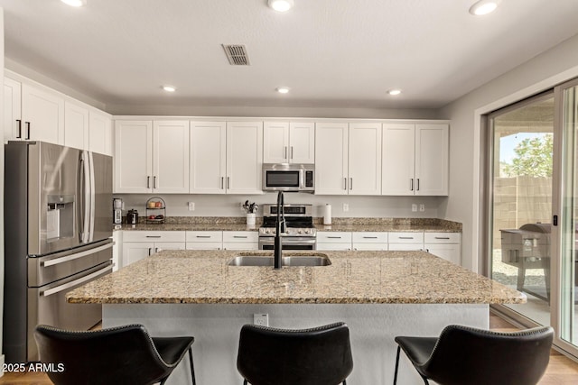 7858 W Fetlock Trl, Peoria, AZ 85383 - kitchen with appliances with stainless steel finishes, white cabinetry, light stone counters, a kitchen breakfast bar, and recessed lighting