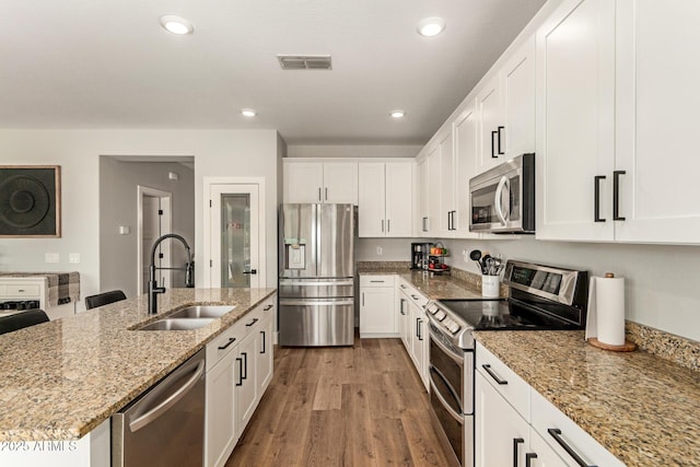 7858 W Fetlock Trl, Peoria, AZ 85383 - kitchen with stainless steel appliances, white cabinets, recessed lighting, light wood-type flooring, and light stone countertops