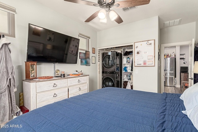 7858 W Fetlock Trl, Peoria, AZ 85383 - bedroom with stacked washing machine and dryer, freestanding refrigerator, and a ceiling fan