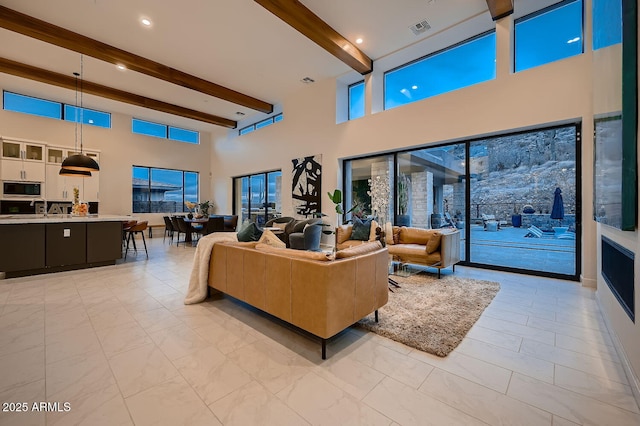 living room featuring a towering ceiling, plenty of natural light, and beam ceiling