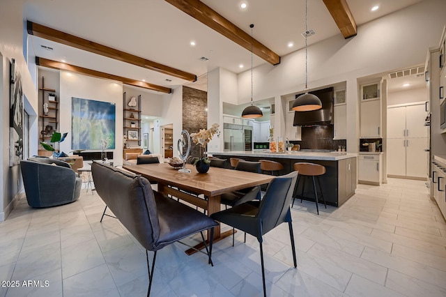 dining area with beam ceiling and a towering ceiling