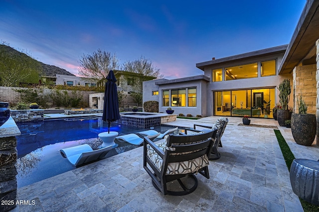 patio terrace at dusk with a swimming pool with hot tub