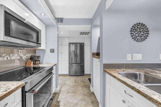 7625 E Camelback Rd Unit B138, Scottsdale, AZ 85251 - kitchen featuring stainless steel appliances, white cabinetry, light stone counters, decorative backsplash, and baseboards