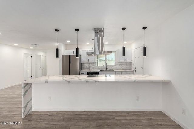 kitchen with kitchen peninsula, decorative light fixtures, white cabinetry, and stainless steel refrigerator