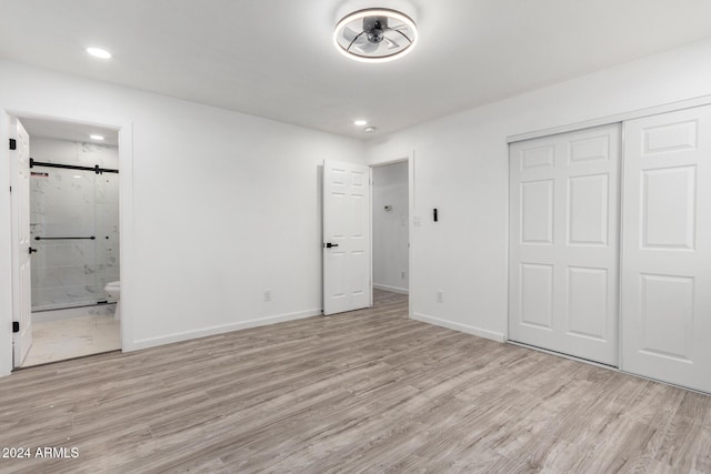 unfurnished bedroom with light hardwood / wood-style flooring, ensuite bath, and a closet