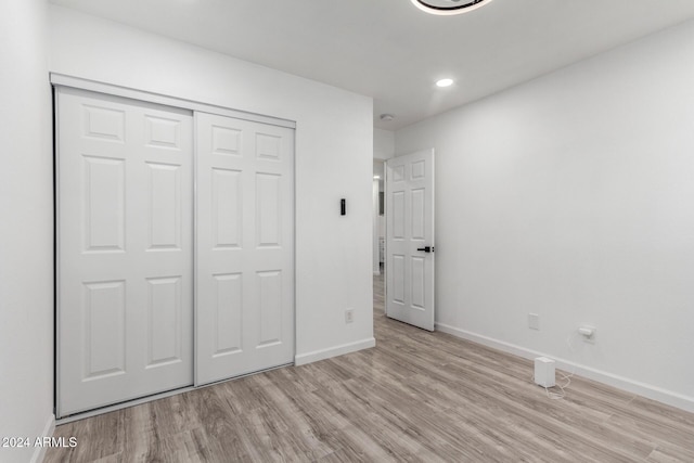 unfurnished bedroom featuring a closet and light wood-type flooring