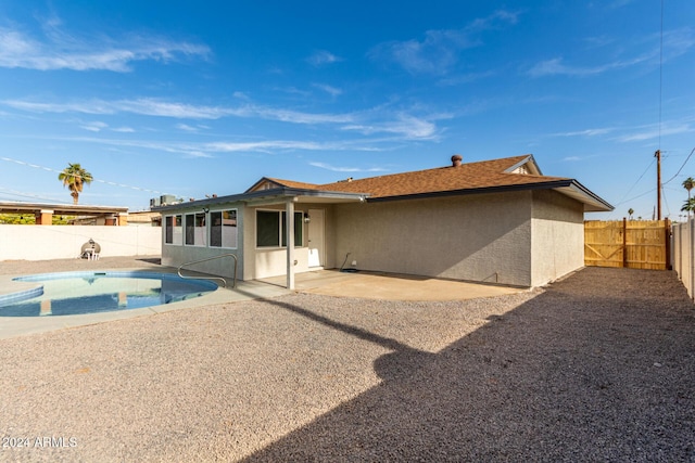 rear view of property with a fenced in pool and a patio area