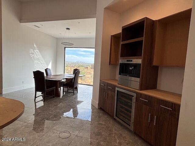 kitchen featuring hanging light fixtures, beverage cooler, and stainless steel oven