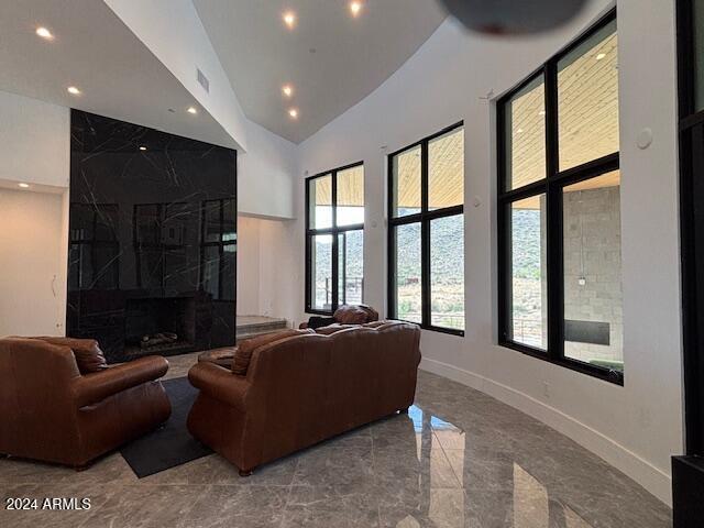 living room with a towering ceiling and a high end fireplace