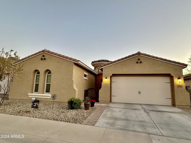 mediterranean / spanish house featuring a tile roof, driveway, an attached garage, and stucco siding