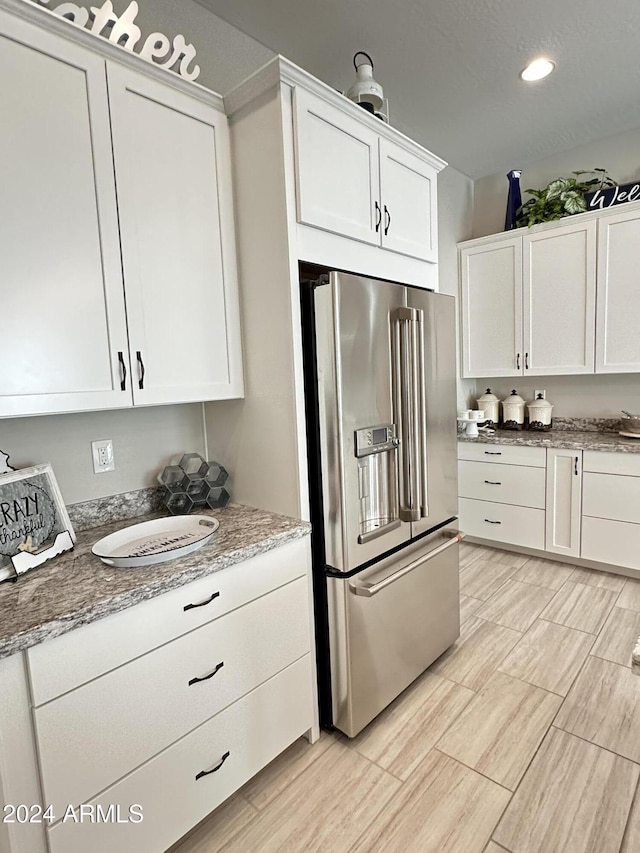 kitchen featuring white cabinetry, stone countertops, and high quality fridge