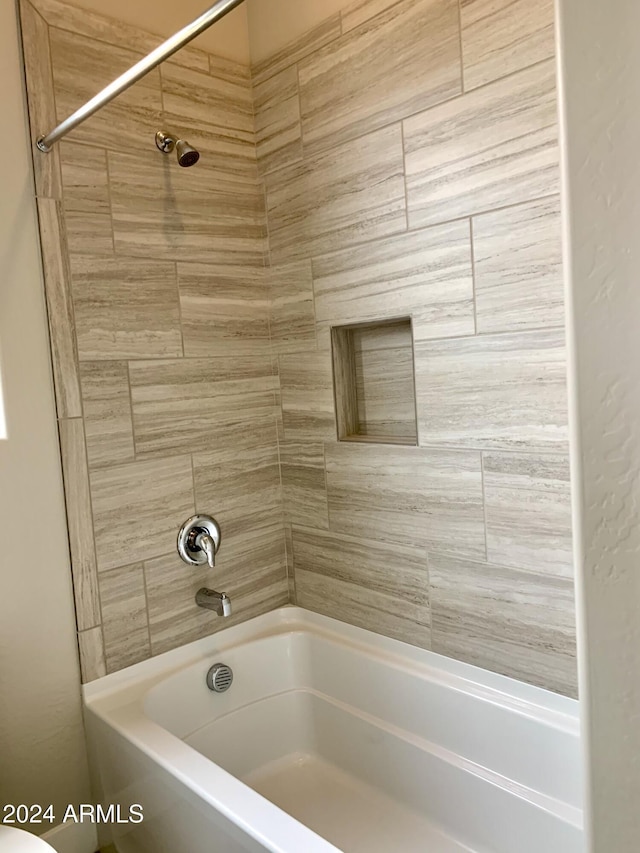 bathroom with toilet and tiled shower / bath