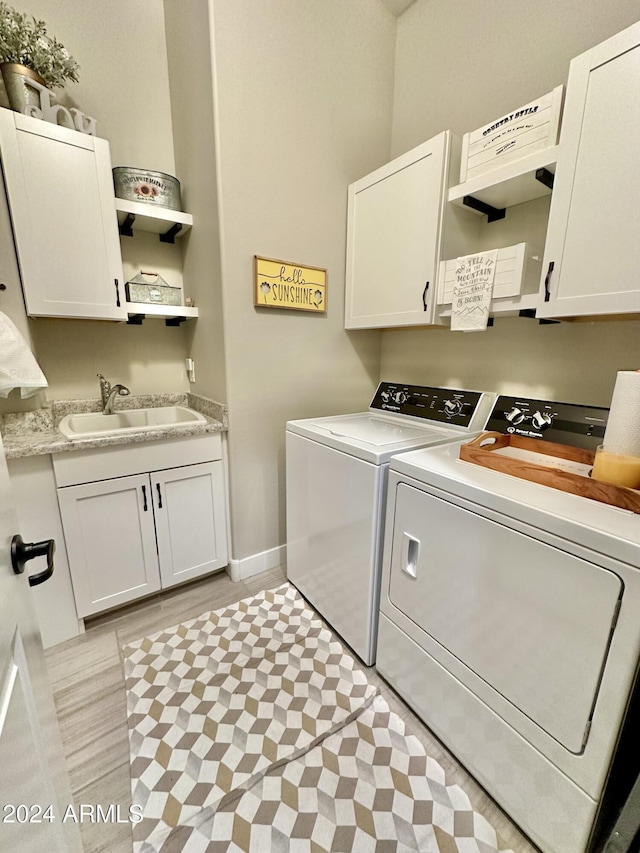 laundry room with light hardwood / wood-style floors, cabinets, sink, and washing machine and clothes dryer