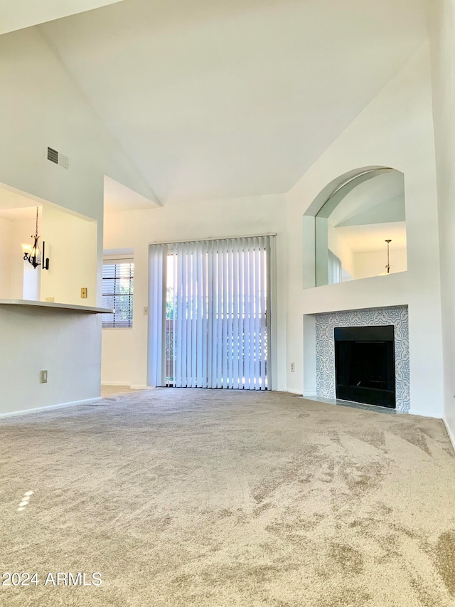 unfurnished living room featuring a fireplace, carpet floors, and high vaulted ceiling