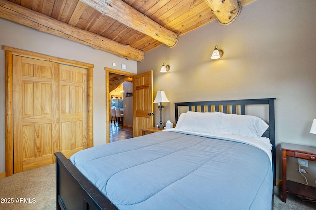 carpeted bedroom featuring beam ceiling, wood ceiling, and a closet