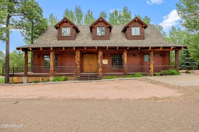 log home with covered porch, concrete driveway, and roof with shingles