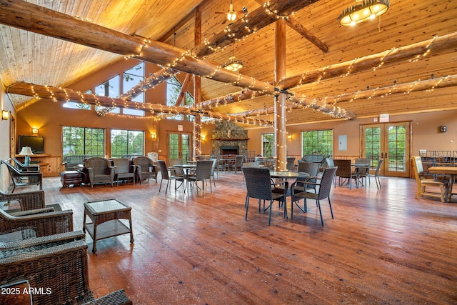 dining room with hardwood / wood-style floors, a stone fireplace, french doors, wooden ceiling, and beamed ceiling