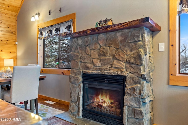 interior space featuring a fireplace, wood finished floors, baseboards, and vaulted ceiling