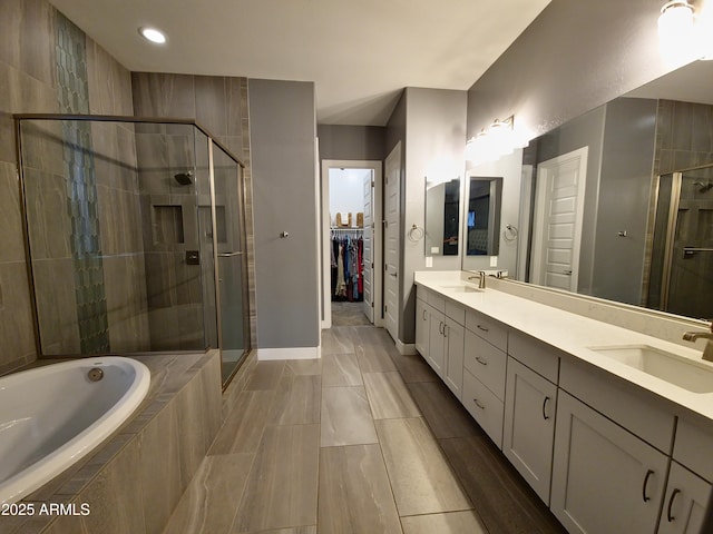 9187 W Parkside Ln, Peoria, AZ 85383 - bathroom with double vanity, a stall shower, a bath, a spacious closet, and baseboards