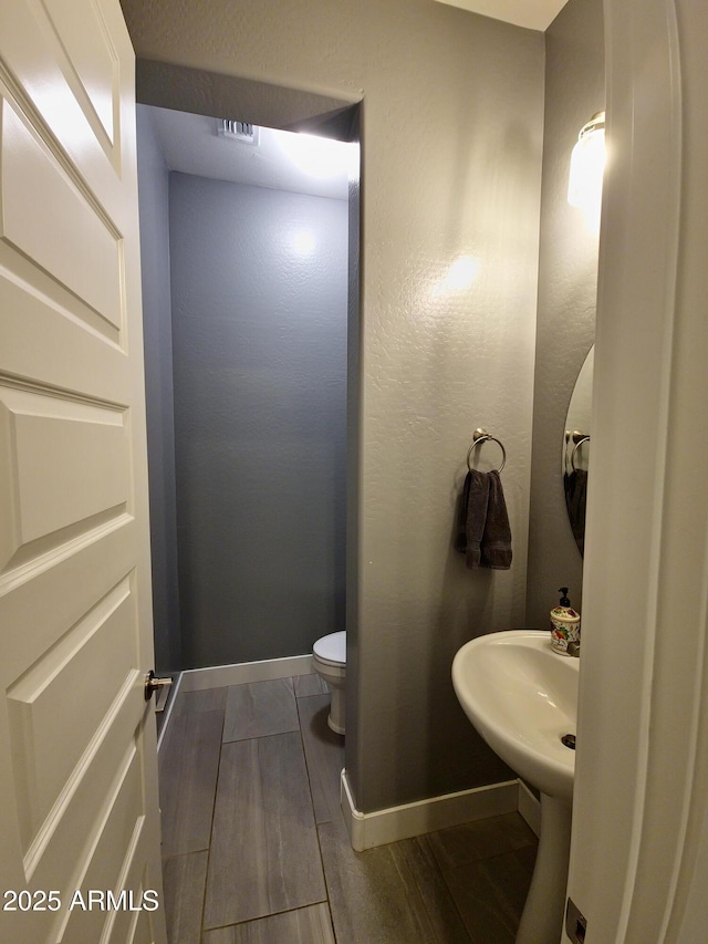 9187 W Parkside Ln, Peoria, AZ 85383 - bathroom featuring toilet, baseboards, and wood finished floors