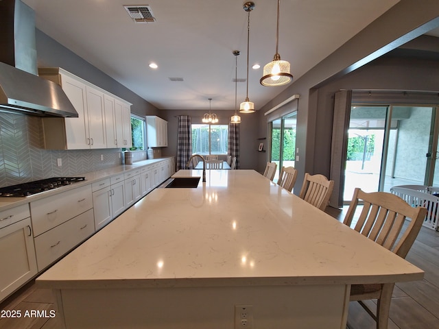 9187 W Parkside Ln, Peoria, AZ 85383 - kitchen featuring wall chimney exhaust hood, gas cooktop, a spacious island, plenty of natural light, and recessed lighting