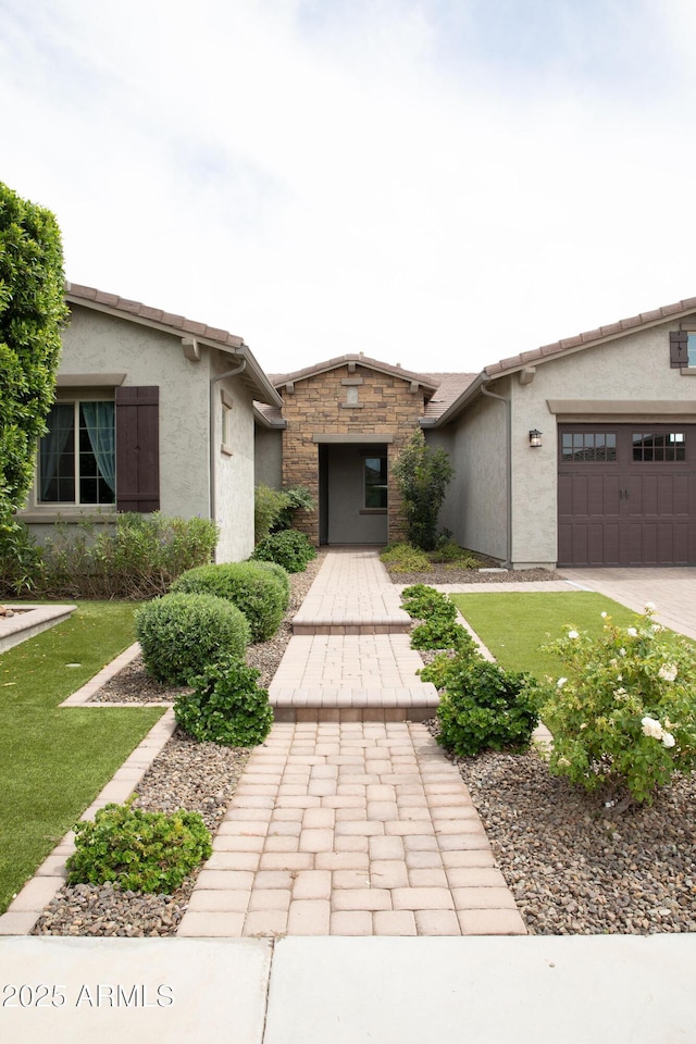 9187 W Parkside Ln, Peoria, AZ 85383 - view of front of house featuring stucco siding, a garage, a front yard, and stone siding