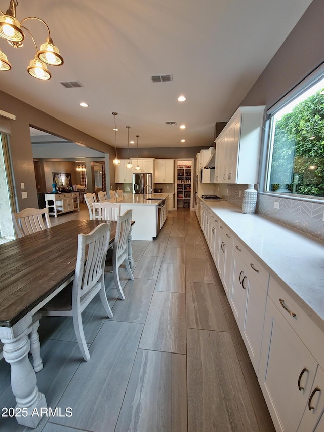 9187 W Parkside Ln, Peoria, AZ 85383 - kitchen with stainless steel fridge, white cabinets, light countertops, pendant lighting, and recessed lighting