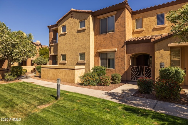 mediterranean / spanish home featuring a tiled roof, a front lawn, and stucco siding