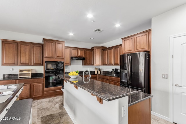 kitchen with visible vents, brown cabinetry, an island with sink, and black appliances