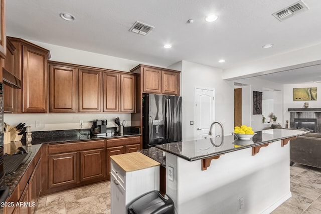 kitchen with visible vents, open floor plan, a breakfast bar, and fridge with ice dispenser