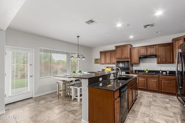 kitchen featuring visible vents, a sink, a kitchen island with sink, and black appliances