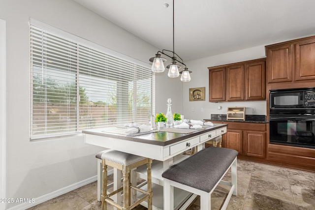 kitchen featuring stone finish floor, dark countertops, brown cabinets, baseboards, and black appliances