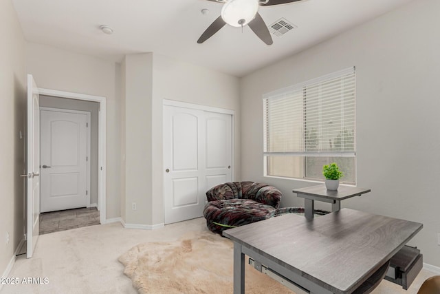 carpeted office space featuring baseboards, a ceiling fan, and visible vents
