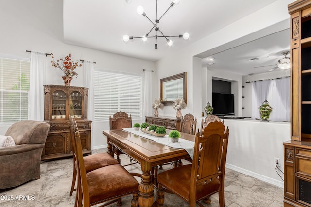 dining area with baseboards and ceiling fan with notable chandelier