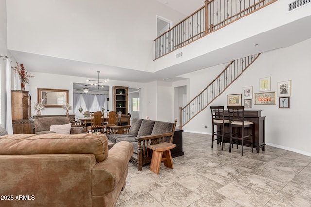 living room featuring a notable chandelier, a high ceiling, visible vents, and baseboards