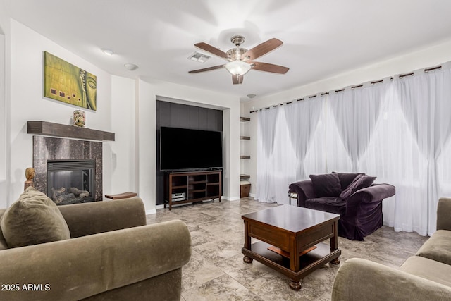 living area with visible vents, a ceiling fan, and a high end fireplace