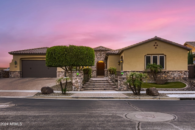 mediterranean / spanish house with stucco siding, decorative driveway, a garage, and a tiled roof