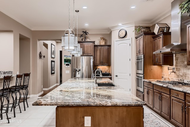 kitchen featuring wall chimney range hood, ornamental molding, appliances with stainless steel finishes, and a sink